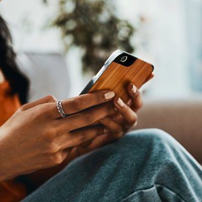 Cropped shot of a woman using a smartphone while relaxing on the sofa at home